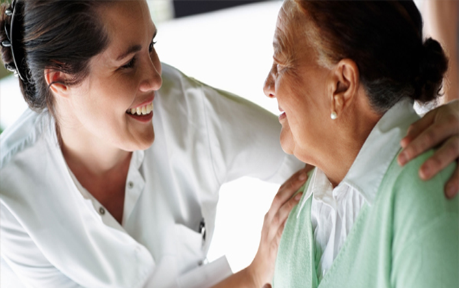 A nurse offers empathetic nursing care services by smiling warmly at an elderly patient.