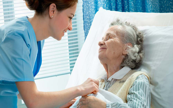 An elderly patient in a hospital bed receives special care and attention from a home-attending nurse