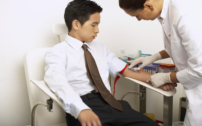 A doctor draws blood from a man's arm, checking for a home blood collection draw.