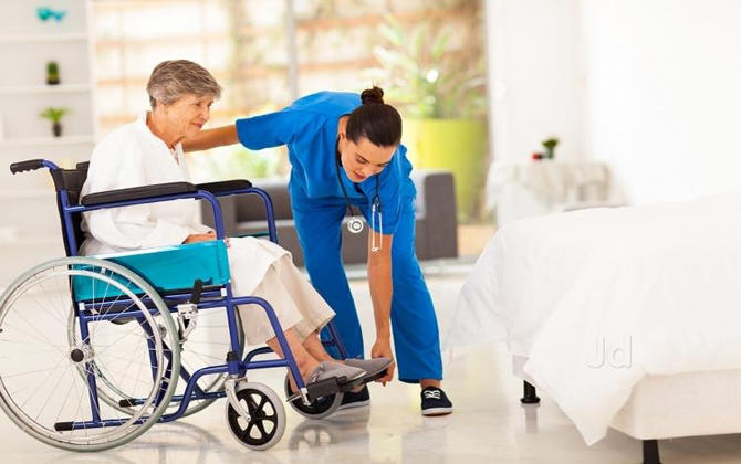 A nurse provides equipment for medical treatment and support to an elderly woman in a wheelchair