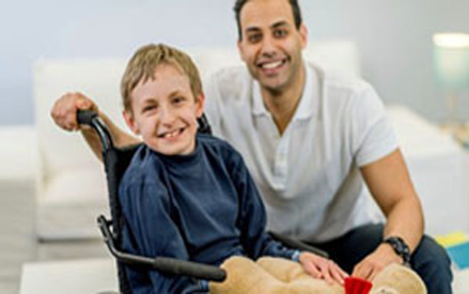 A man in a wheelchair holds a boy, symbolising physical disability home care services.