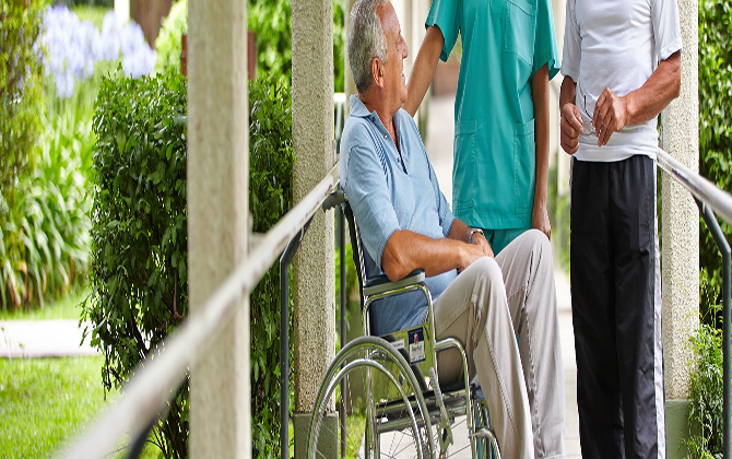 A man in a wheelchair conversing with two nurses, representing physical disability home care services