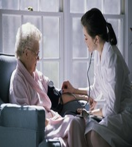 An elderly woman is receiving a blood pressure check from a home-assisted nurse.
