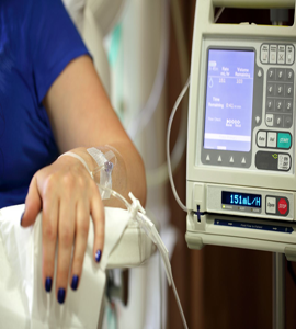 A female patient in a hospital room is receiving IV treatments and being monitored by technology.