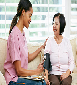A home nurse checks a patient's blood pressure and discusses with her their healthcare solutions.