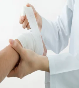A nurse with a bandaged hand, indicating an injury or wound medical wrapping bandages the hand