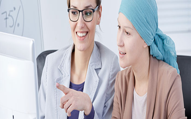 An old woman receiving treatment for cancer is supported by a nurse in a hospital environment